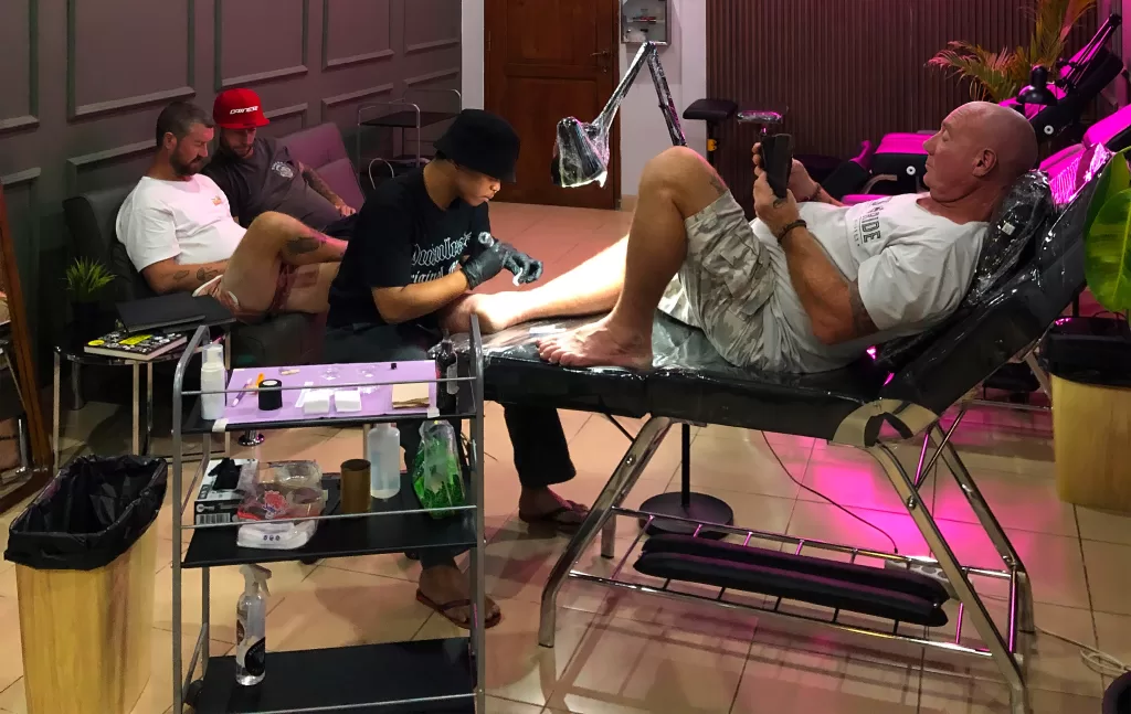 Professional tattoo artist working on customer sleeve tattoo at Primitive Tattoo Bali studio in Seminyak