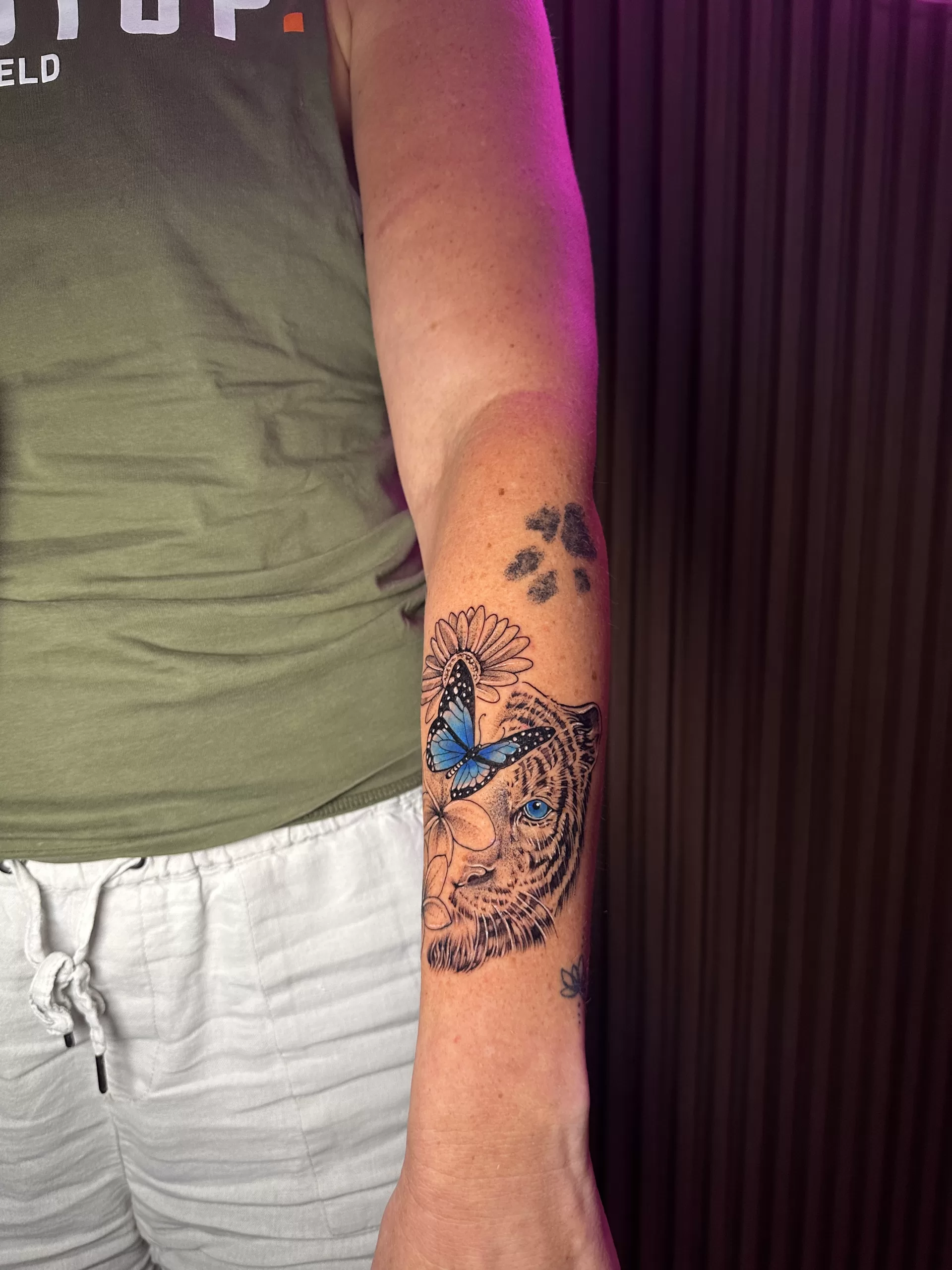 Tiger and flower women's arm tattoo by Primitive Tattoo Bali - fierce animal portrait with floral elements Seminyak
